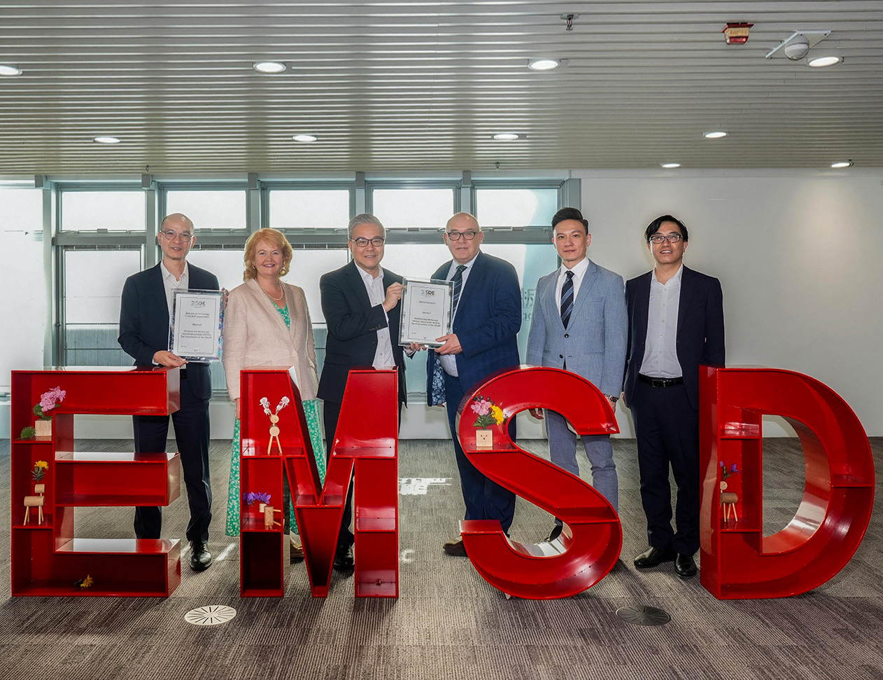 機電署署長潘國英先生（左三）、副署長/營運服務周厚強先生（右一）和副署長/規管服務陳柏祥先生（左一）在機電署總部從英國屋宇裝備工程師學會代表手中接過獎狀。